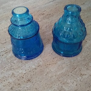 Peut inclure: Deux bouteilles en verre bleu avec une surface textur&eacute;e. Les bouteilles sont vides et ont un aspect vintage.