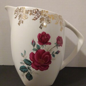 May include: White ceramic pitcher with a gold floral design around the top and a red rose floral design on the front.