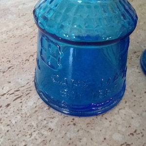 Peut inclure: Une bouteille en verre bleu cobalt avec un dessus arrondi et une surface textur&eacute;e. La bouteille porte l'inscription "CAVENE" et "BY THE".