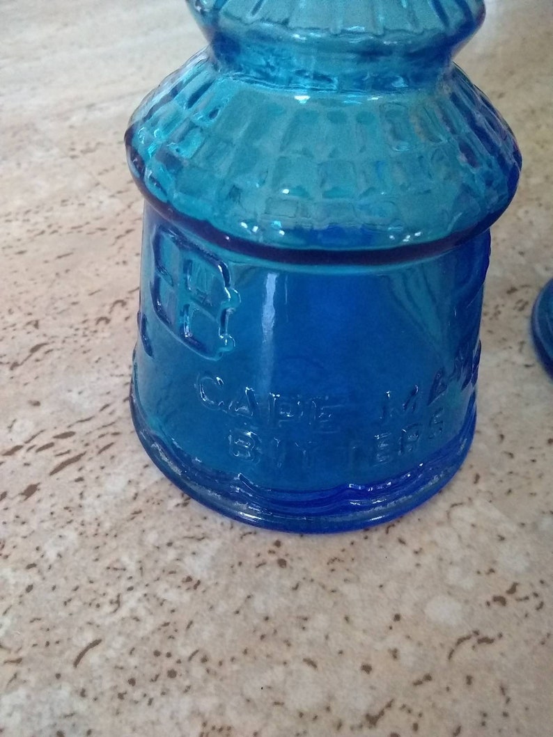 Peut inclure: Une bouteille en verre bleu cobalt avec un dessus arrondi et une surface textur&eacute;e. La bouteille porte l'inscription "CAVENE" et "BY THE".