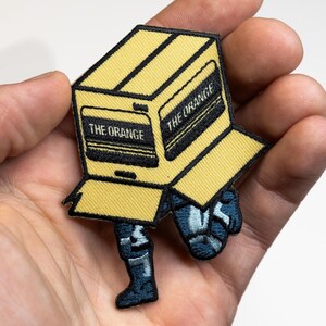 Metal Gear Solid Snake - Caixa de papelão com remendo bordado - 3 x 2,5 polegadas - a caixa laranja furtiva - emblema de ação de espionagem do Big Boss