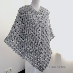 Op de afbeelding: Een grijs gebreid poncho met een v-hals en een kantpatroon. De poncho wordt getoond op een wit mannequin. De tekst "Frisian Knitting" is zichtbaar in de rechterbenedenhoek van de afbeelding.