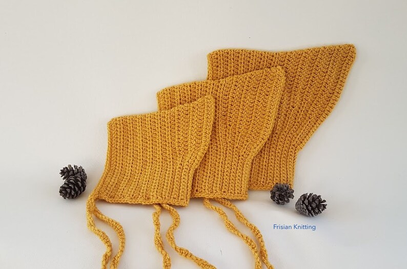 Op de afbeelding: Drie gele gehaakte baby mutsjes met bandjes, in een rij op een wit oppervlak gerangschikt. De mutsjes zijn gemaakt met een eenvoudig steekpatroon en hebben een puntige vorm. De mutsjes zijn een populaire keuze voor baby's en peuters.