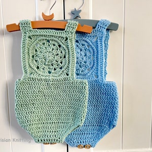 May include: Two crocheted baby onesies, one in a light green color and one in a light blue color. Both onesies have a crocheted square design on the front with a circular pattern in the center.