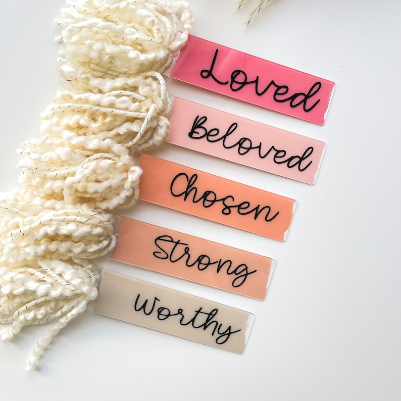Puede incluir: Cinco marcadores de libros de acr&iacute;lico rosa y beige con las palabras "Loved", "Beloved", "Chosen", "Strong" y "Worthy" escritas en cursiva negra.