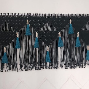 May include: Black and teal macrame wall hanging with wooden beads and tassels.