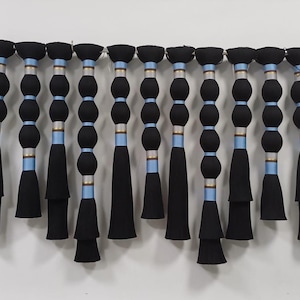 May include: A row of 14 black tassels with blue and gold accents hanging from a metal rod. Each tassel has a series of round, black beads.