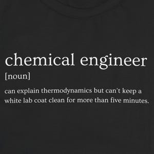 May include: Black t-shirt with the definition of "chemical engineer" printed in white. The definition includes the word "noun" and a humorous statement about thermodynamics and lab coats.