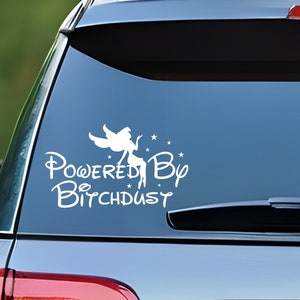 May include: White vinyl sticker with a fairy silhouette and the text "Powered By Bitchdust" on a blue car window.