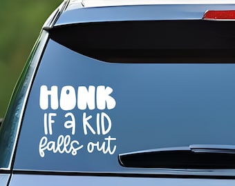 May include: A white vinyl sticker on the back window of a silver car that says "HONK IF A KID FALLS OUT".