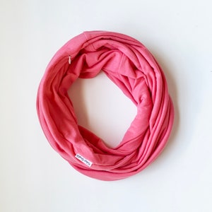 May include: A pink infinity scarf with a small white tag that says "Cozy & Happy".