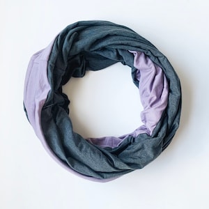 May include: A soft, gray and purple infinity scarf. The scarf is made of a stretchy fabric and can be worn in a variety of ways.