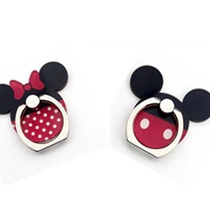May include: Two phone ring holders featuring a cartoon mouse design. One has a red bow and white polka dots, the other has a red and white face design. Both have black ears and a silver ring.