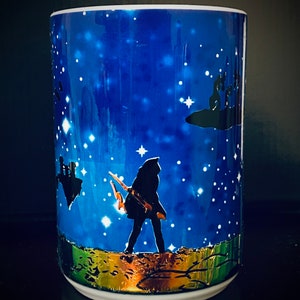 May include: A white ceramic mug with a blue and gold design. The mug features a silhouette of a person walking on a path with a starry night sky in the background.