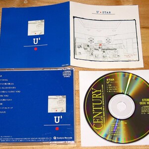 May include: A blue CD case with a white label featuring the title "U' STAR" and a list of song titles in Japanese. The CD is a gold disc with the text "CENTURY" and "STEREO CECC 10307" printed on it.