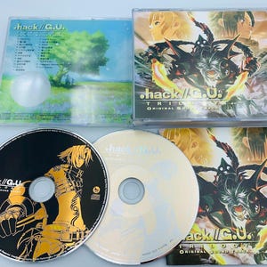 May include: Two black and silver compact discs with a black and white illustration of a character on the left disc. The disc on the right is silver with a black and white illustration of a character on the front cover. The discs are part of a video game soundtrack.