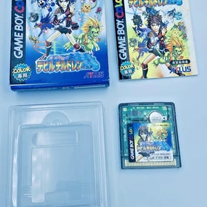 May include: A Game Boy Color video game set featuring the game "Devil Children". The set includes the game cartridge, box, and instruction manual. The box and manual feature colorful illustrations of characters and the game title.