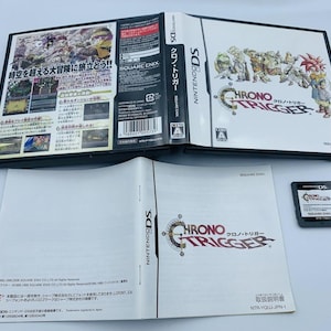 May include: A Nintendo DS game cartridge for Chrono Trigger, a role-playing game. The cartridge is black with a red and white label. The label features the game's title, Chrono Trigger, and a stylized image of a character from the game. The cartridge is in a protective case.