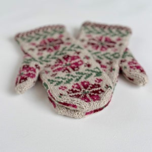 May include: A pair of knitted mittens with a beige background and a pattern of pink and green flowers.