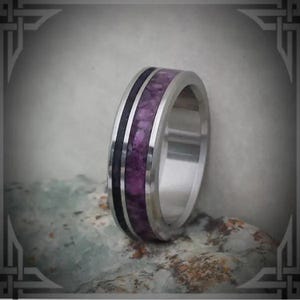 May include: A stainless steel ring with a purple and black wood inlay. The ring has a polished finish and a beveled edge.