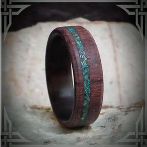 May include: A dark brown wooden ring with a thin turquoise inlay. The ring is smooth and polished.