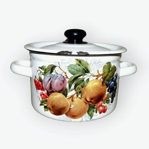 May include: White enamel pot with a black lid and a fruit design. The design features plums, apples, grapes, and strawberries.