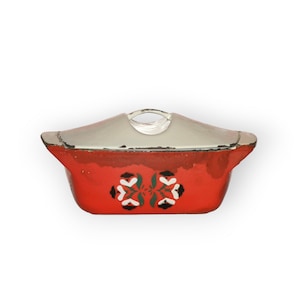 May include: Red enamelware casserole dish with a white lid and a floral design. The dish has a handle on the lid and two handles on the sides.
