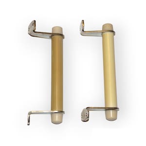 May include: Two beige ceramic door pulls with silver metal brackets. The pulls are cylindrical and have a rounded end. The brackets are L-shaped and have two holes for mounting.