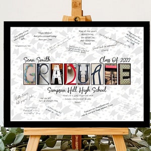 May include: A framed graduation sign with the word "GRADUATE" spelled out in colorful letters. The sign includes the graduate's name, school, and class year. It is displayed on a small wooden easel, with greenery in the foreground.