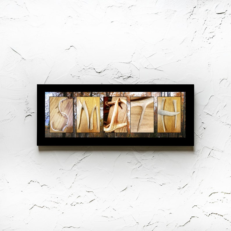 May include: A framed print of the name "SMITH" spelled out using antlers. The background is a blurred image of a forest.