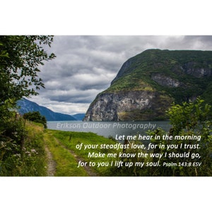 May include: A scenic view of a fjord with a path leading to the water. The sky is cloudy and the mountains are green. The text "Let me hear in the morning of your steadfast love, for in you I trust. Make me know the way I should go, for to you I lift up my soul. Psalm 143:8 ESV" is superimposed on the image.
