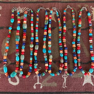 May include: Seven colorful beaded necklaces with turquoise, red, orange, and blue beads. The necklaces are made of natural stones and are strung on silver chains.