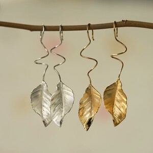 May include: Two pairs of leaf-shaped earrings with a twisted wire design. One pair is silver and the other is gold.