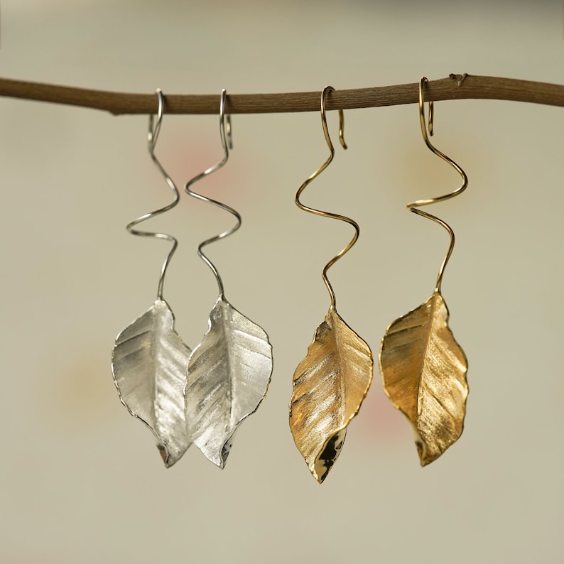 May include: Two pairs of leaf-shaped earrings with a twisted wire design. One pair is silver and the other is gold.