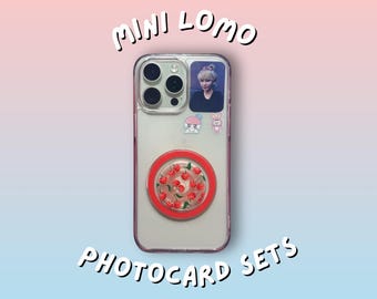 May include: Clear phone case with a photo of a person, stickers, and a red cherry design pop socket. The words "MINI LOMO" and "PHOTOCARD SETS" are written in white, stylized text.
