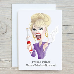May include: A birthday card featuring a cartoon illustration of a woman with blonde hair, wearing a purple jacket and holding a bottle of alcohol and a cigarette. The text on the card reads "Sweetie, Darling Have a Fabulous Birthday!"