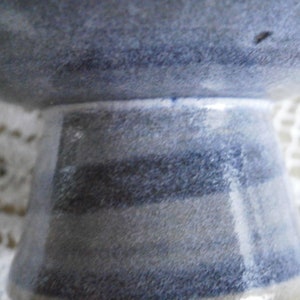 May include: A blue and white ceramic bowl with a striped base. The bowl is glazed and has a rustic look.