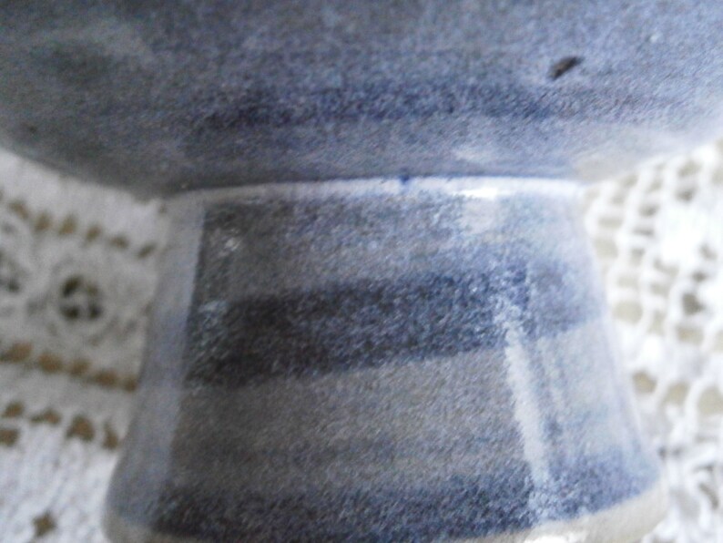 May include: A blue and white ceramic bowl with a striped base. The bowl is glazed and has a rustic look.