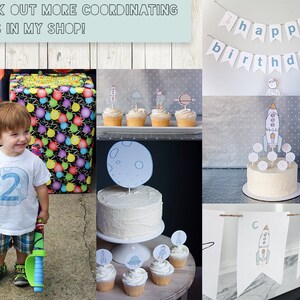 May include: A two-year-old birthday party with a space theme. The party decorations include a banner that says "happy birthday", a cake with a rocket ship topper, and cupcakes with astronaut and spaceship toppers. The cake is white with a white frosting and is decorated with blue and white sprinkles. The cupcakes are also white with white frosting and are decorated with blue and white sprinkles. The banner is white with blue lettering. The party decorations are on a gray background.