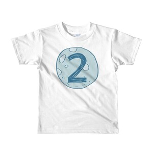 May include: White t-shirt with a blue moon graphic featuring the number 2.