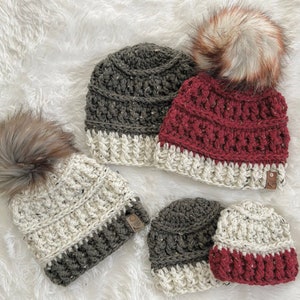 Peut inclure: Quatre bonnets en crochet dans différentes combinaisons de couleurs. Deux bonnets sont blancs et gris, un est rouge et blanc, et un est gris et blanc. Les bonnets ont des pompons.