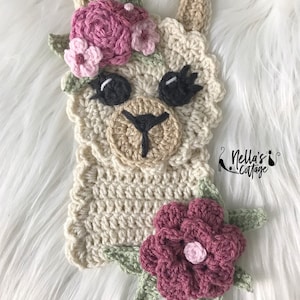 May include: Crocheted llama with a pink and green flower crown and a pink flower on the bottom. The llama is cream colored and has black eyes and a black nose.