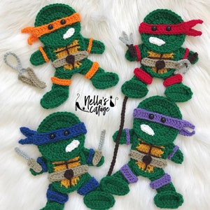 May include: Four crocheted Teenage Mutant Ninja Turtle characters. Each turtle is green with a different colored mask and bandana. The turtles are holding their signature weapons. The characters are on a white fuzzy background.