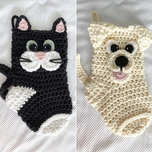 May include: Two crocheted Christmas stockings, one shaped like a black cat and the other shaped like a white dog. Both stockings have embroidered faces with black eyes and pink noses.