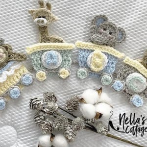 May include: Crocheted train set with animal toppers, including a giraffe, elephant, lion, and monkey. The train cars are in pastel colors of blue, yellow, and green. The image also includes cotton and pinecones.
