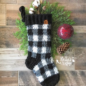 May include: A black and white checkered crochet stocking with a black cuff and a brown leather tag that says "NC".