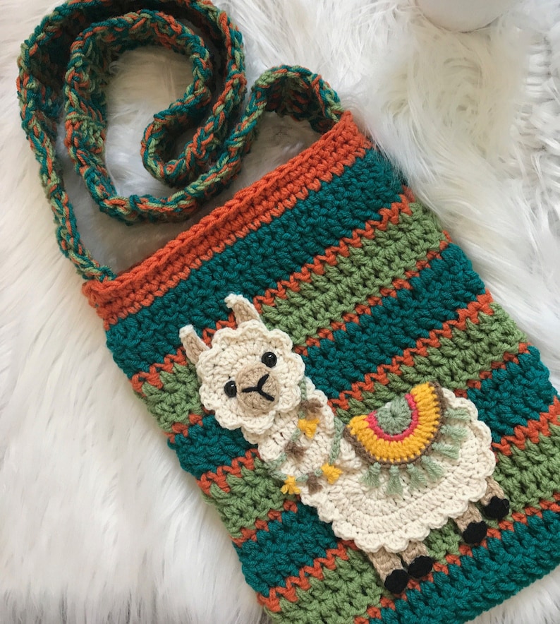 May include: A teal, green, and orange crocheted crossbody bag with a white crocheted llama applique. The llama has a rainbow-colored saddle and a fringe.