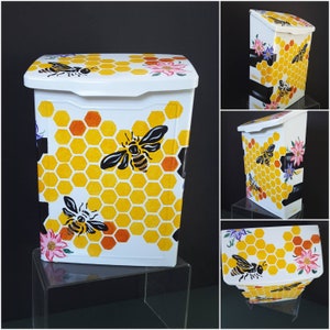 May include: White mailbox with a honeycomb pattern and bee illustrations. The mailbox has a yellow and orange honeycomb pattern with black bees and flowers.