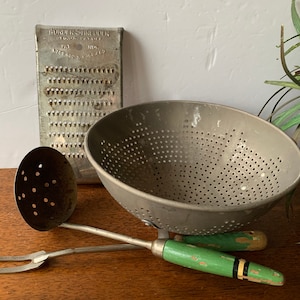 May include: Vintage kitchen tools including a metal colander with green handles, a metal ladle with a green handle, and a metal grater with the text "Wonder Shredder, Reg. Pat. Off. Pat. 1,703,405, 1,964,419".