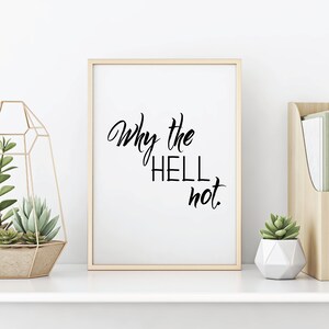 Peut inclure: Une impression encadrée avec le texte "Why the hell not." en écriture cursive noire sur fond blanc.
